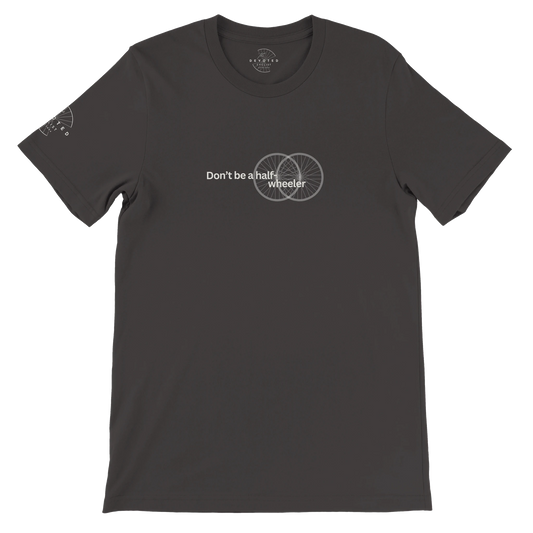 Image of the Half-Wheeler T-shirt in dark grey from The Devoted Cyclists . It says "Don't Be a half-wheeler" in ivory text with the image of two road wheels doubling each other on a transparent background. 